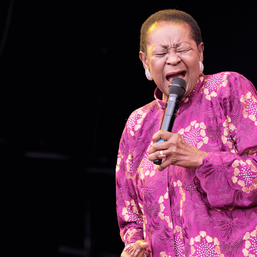 Woman in purple outfit singing into microphone