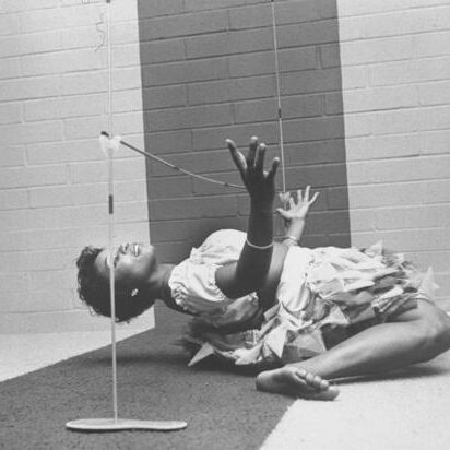 Performer balancing pole with mouth while reclining