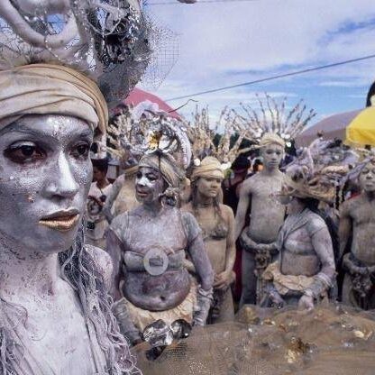 Silver-painted performers wearing headdresses at parade